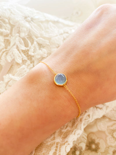 Bride wearing dainty gold bracelet with blue aquamarine stone

