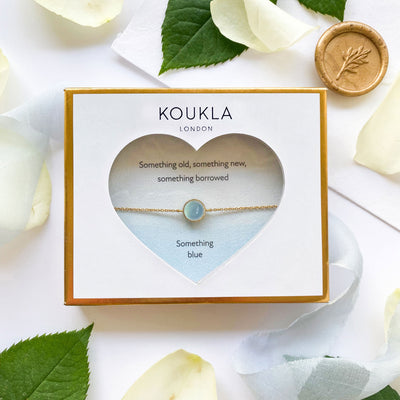 Dainty gold bridal bracelet with blue aquamarine stone in giftable wedding packaging

