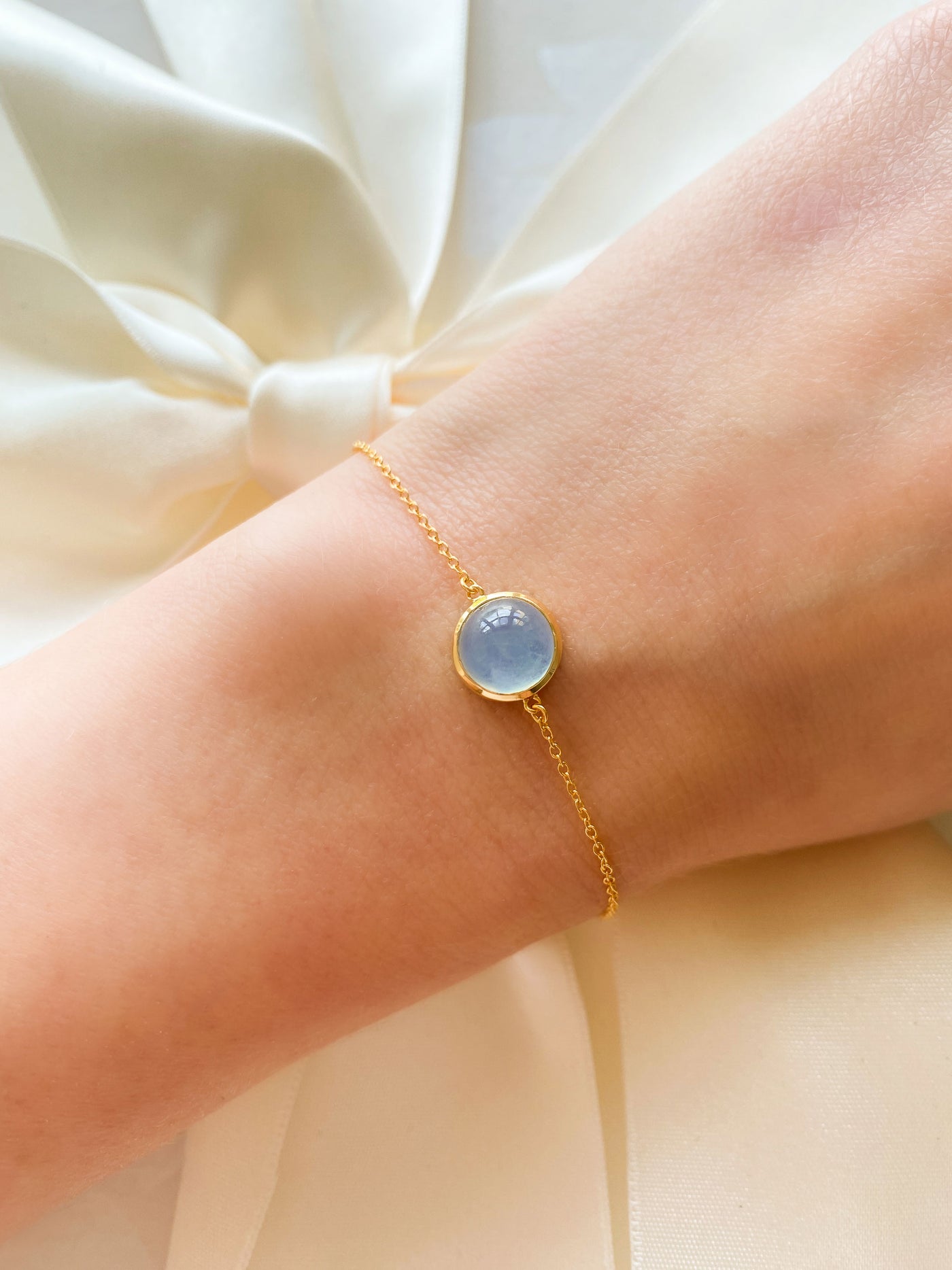 Bride wearing dainty gold bracelet with blue aquamarine stone
