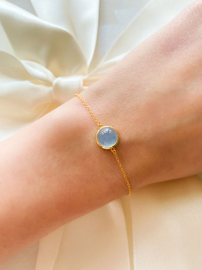 Bride wearing dainty gold bracelet with blue aquamarine stone