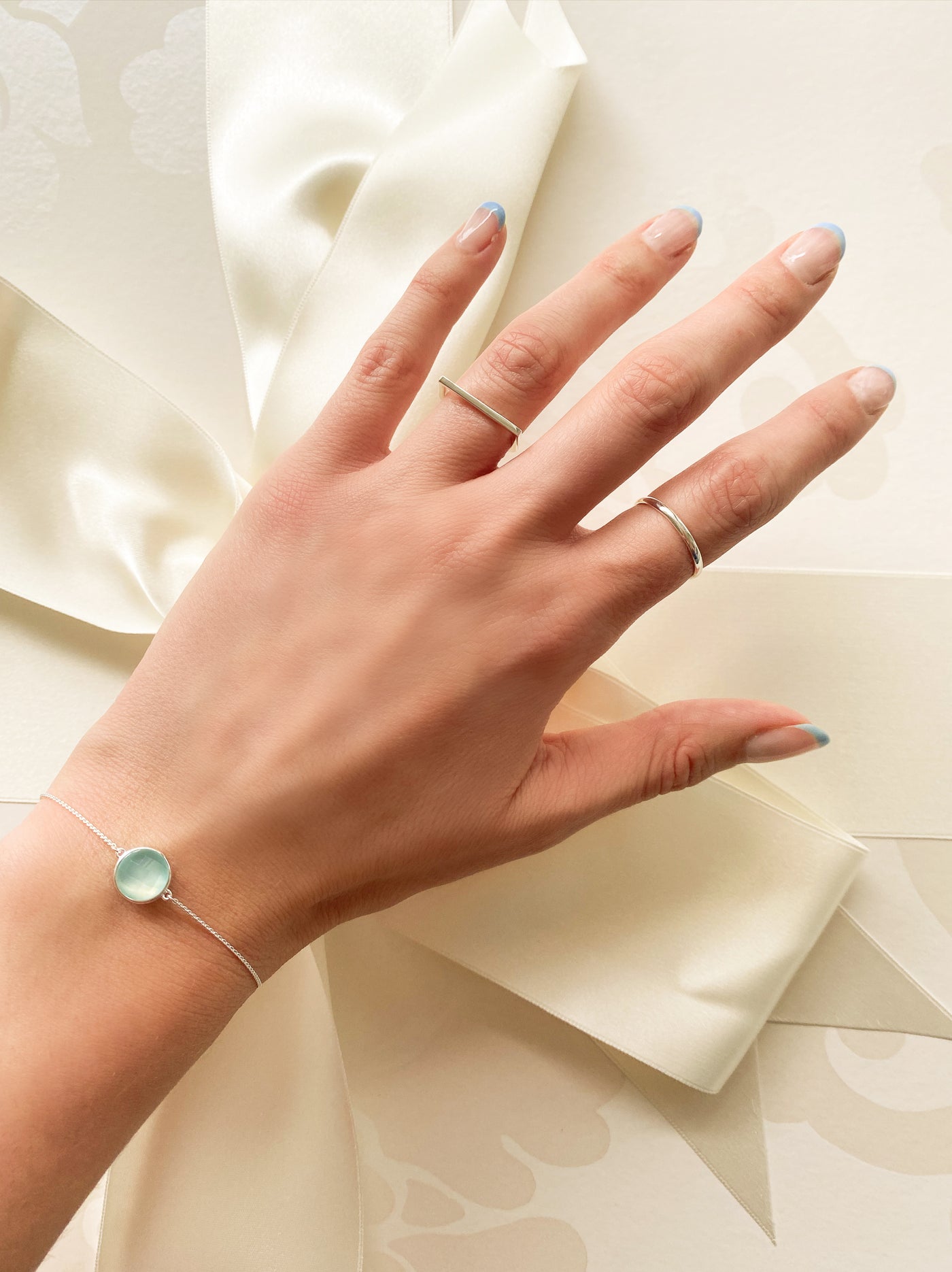 Model wearing silver bridal bracelet with blue aquamarine stone with wedding dress box in background