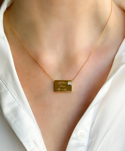 Model wearing gold engraved reversible envelope necklace with CZ crystal