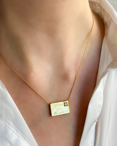 Model wearing gold engraved reversible envelope necklace with CZ crystal