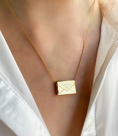 Model wearing gold engraved reversible envelope necklace with CZ crystal