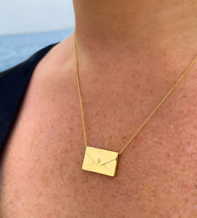 Model wearing gold engraved reversible envelope necklace with CZ crystal