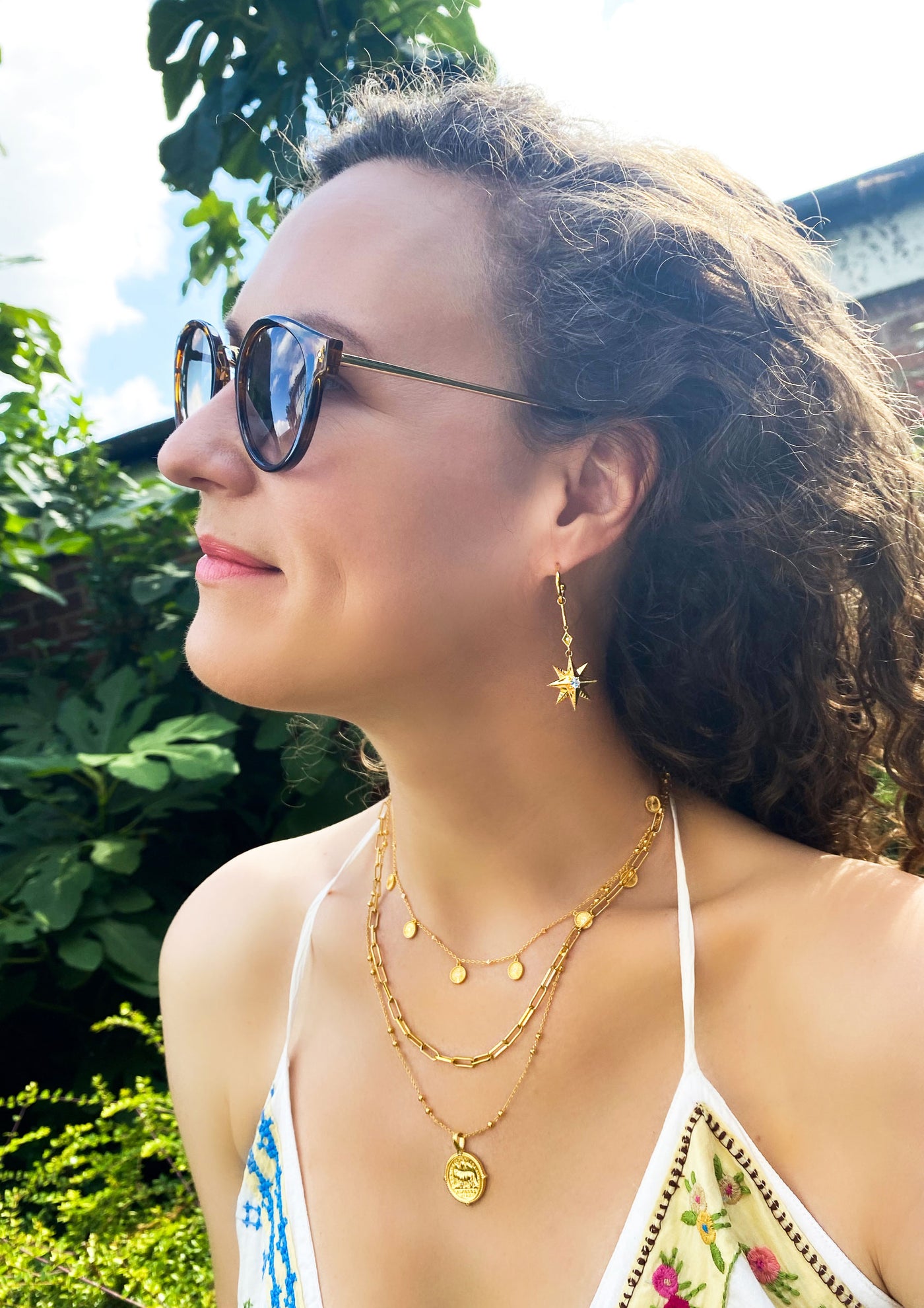 Model wearing statement gold bar star drop hoop earrings with CZ crystals with a choker and layered necklaces