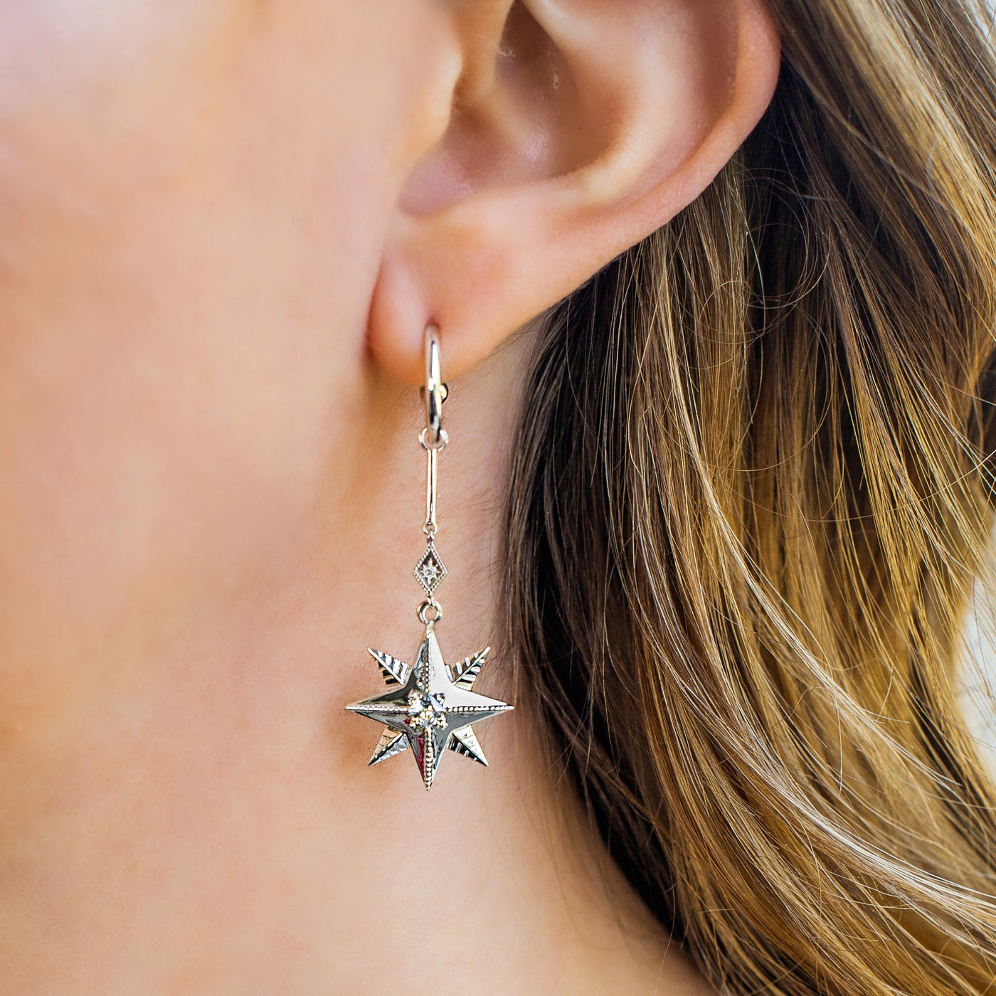 Model wearing statement sterling silver bar star drop hoop earrings with CZ crystals
