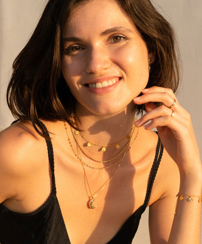 Model wearing layered gold plated sterling silver engraved coin choker, rope necklace, bobble chain and moon pendant 