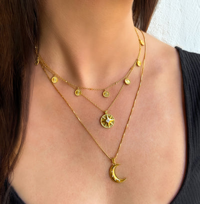 Model wearing gold plated sterling silver 3D engraved star coin necklace with CZ crystal, layered with moon necklace and sun coin choker