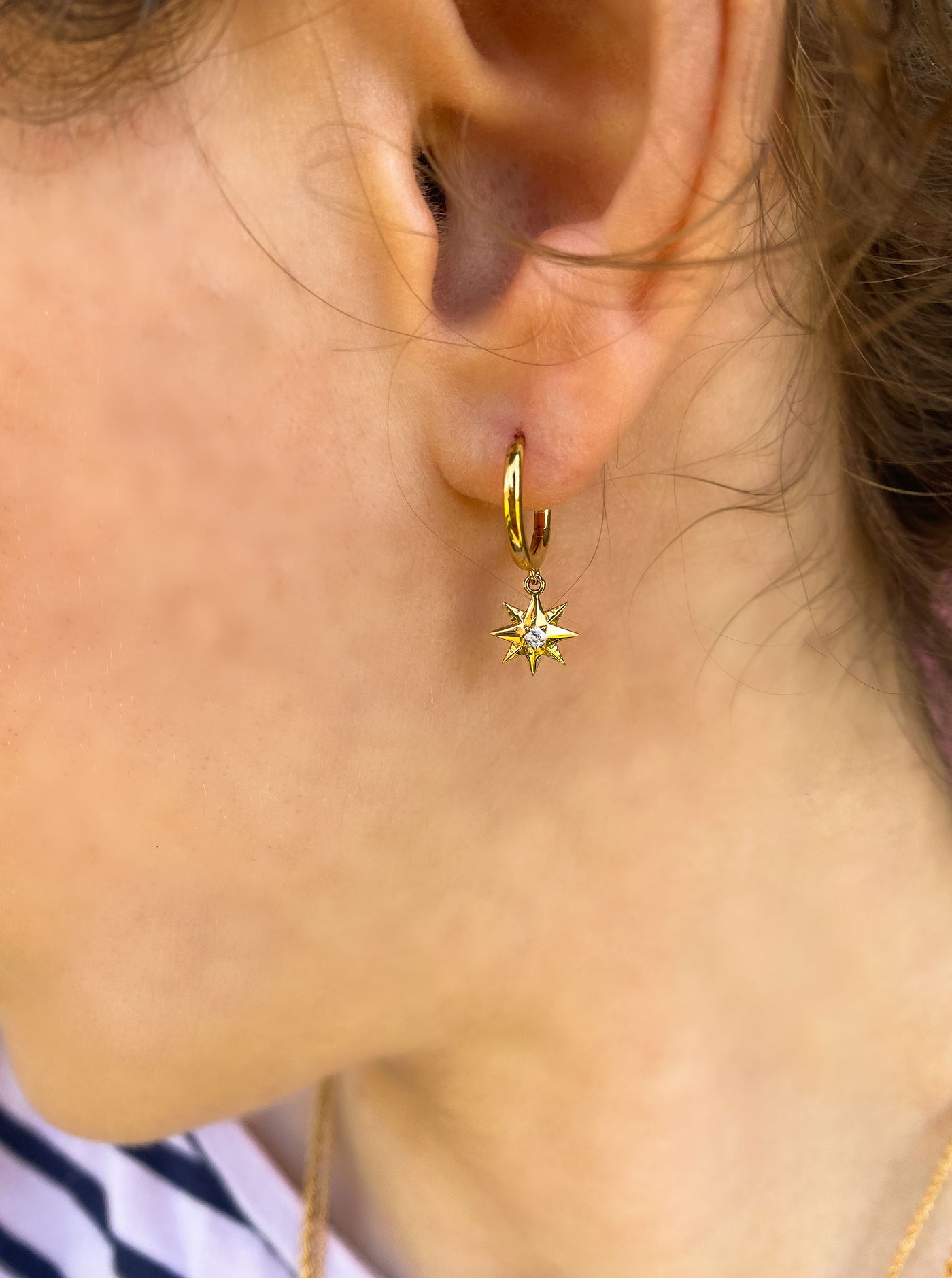 Model wearing mini gold star huggie hoop with CZ crystal