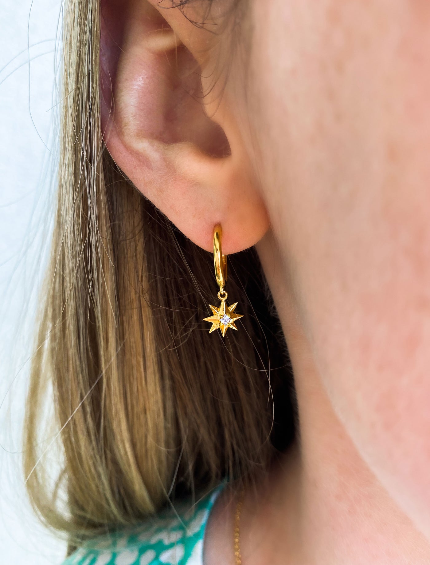 Model wearing mini gold star huggie hoop with CZ crystal