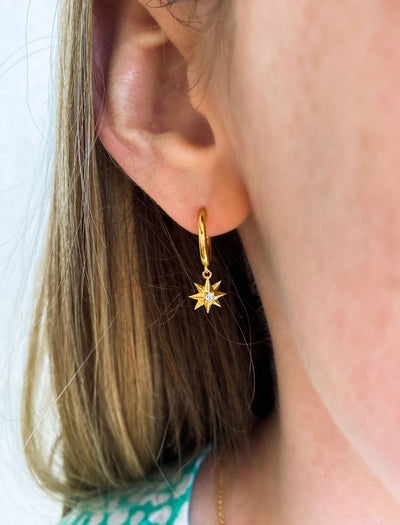 Model wearing mini gold star huggie hoop with CZ crystal