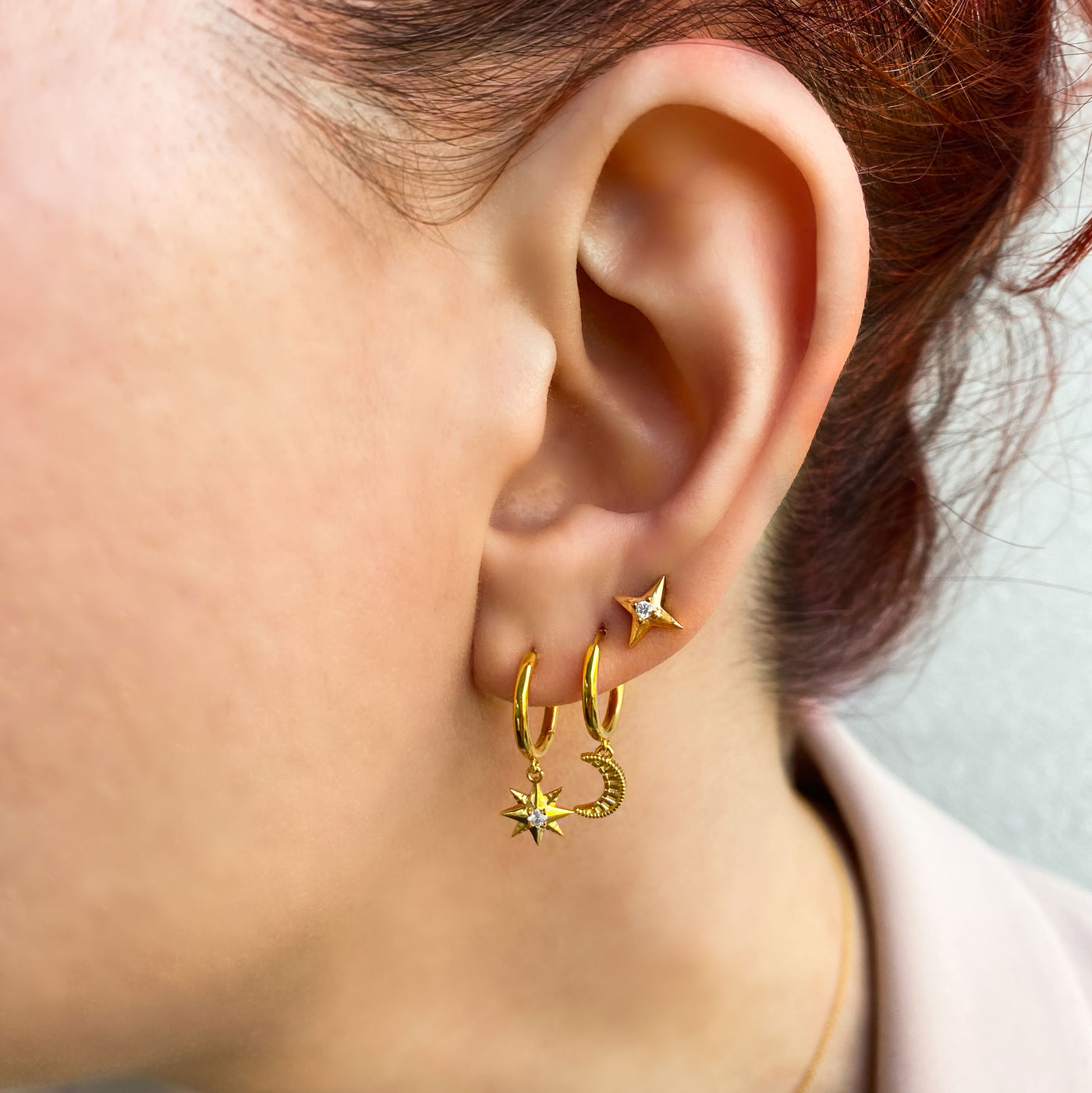Model wearing mini gold star and moon huggie hoops with cz star earring