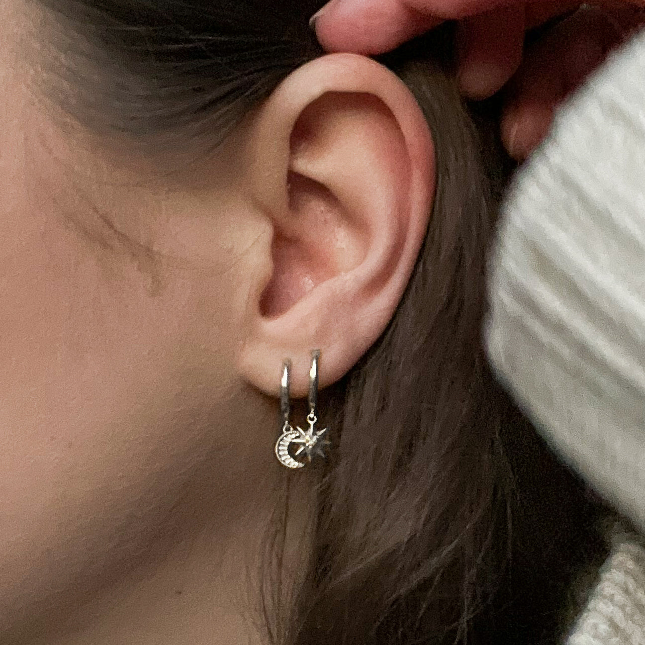 Model wearing sterling silver moon and star mini huggie hoops with CZ crystal