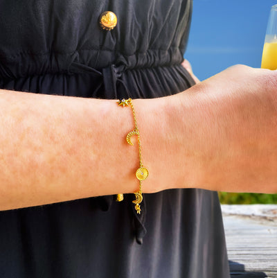 Model wearing gold plated sterling Silver moon and star charm bracelet with CZ crystals
