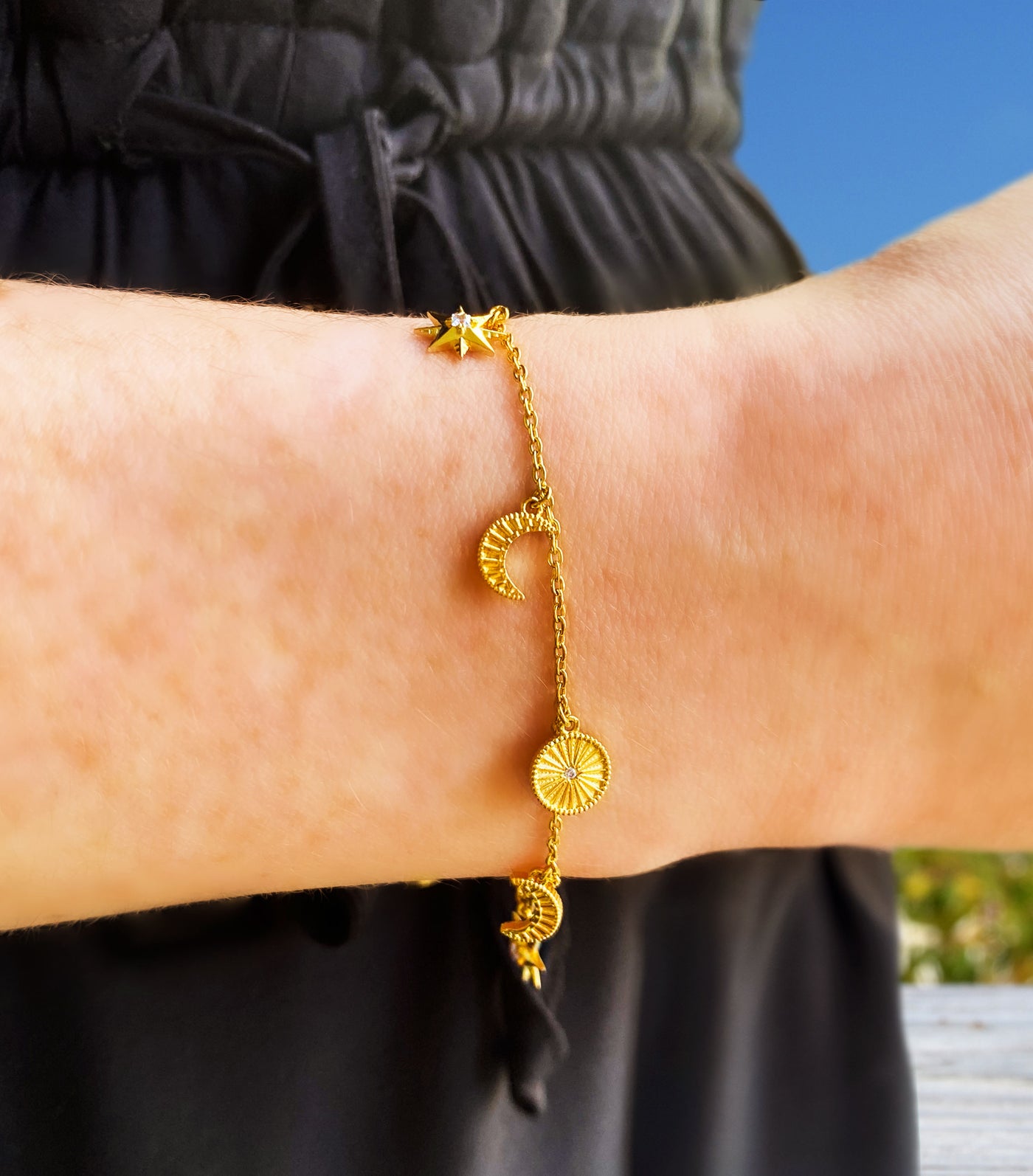Model wearing gold plated sterling Silver moon and star charm bracelet with CZ crystals