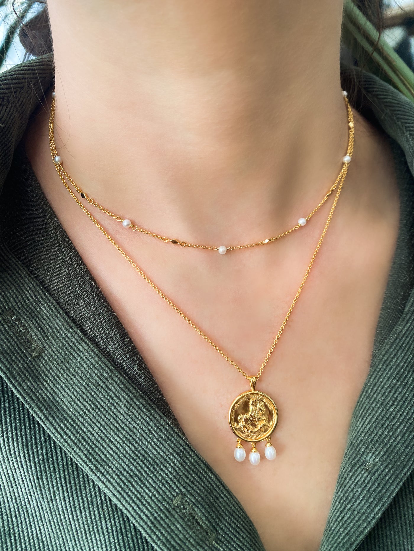 Model wearing gold plated sterling silver engraved horse coin pendant necklace with hanging freshwater pearls and beaded pearl choker 