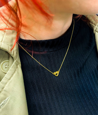 Model wearing 18kt gold plated sterling silver heart knot necklace