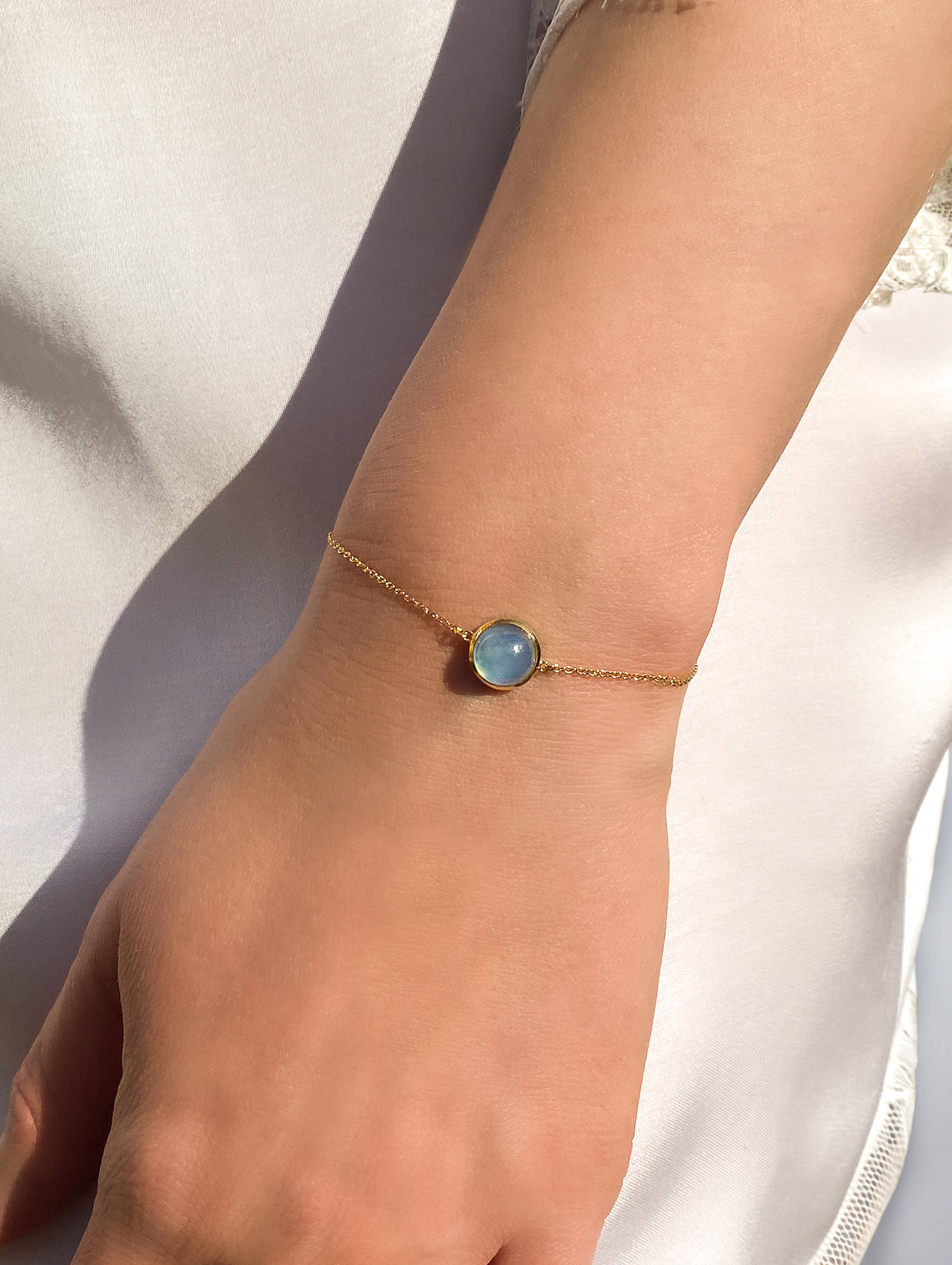 Bride wearing dainty gold bracelet with blue aquamarine stone