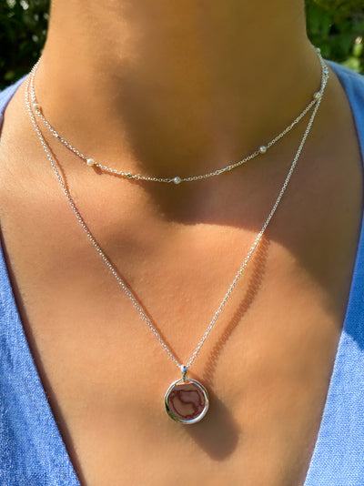 Model wearing silver plain coin pendant necklace and beaded pearl choker 