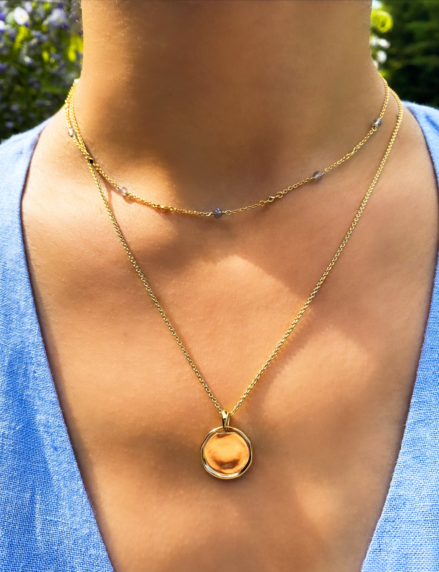 Model wearing gold plain coin pendant necklace and labradorite beaded choker 