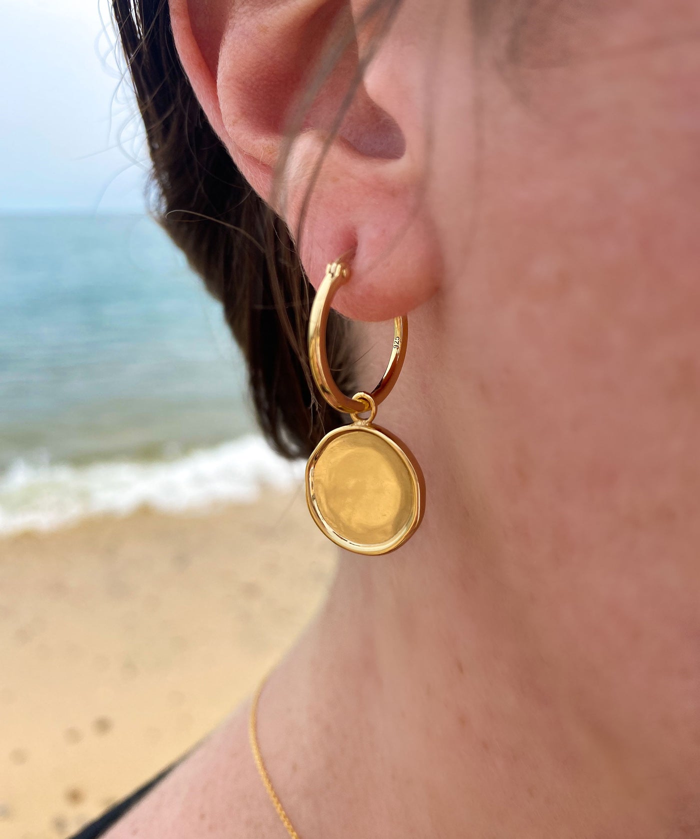 Model wearing simple gold plated sterling silver coin hoop earrings