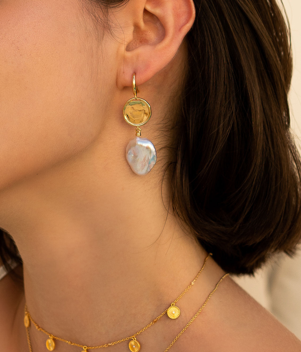 Model wearing gold coin and freshwater pearl drop earrings