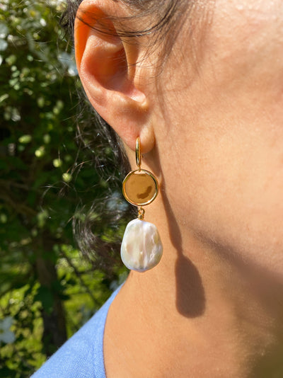 Model wearing gold coin and freshwater pearl drop earrings