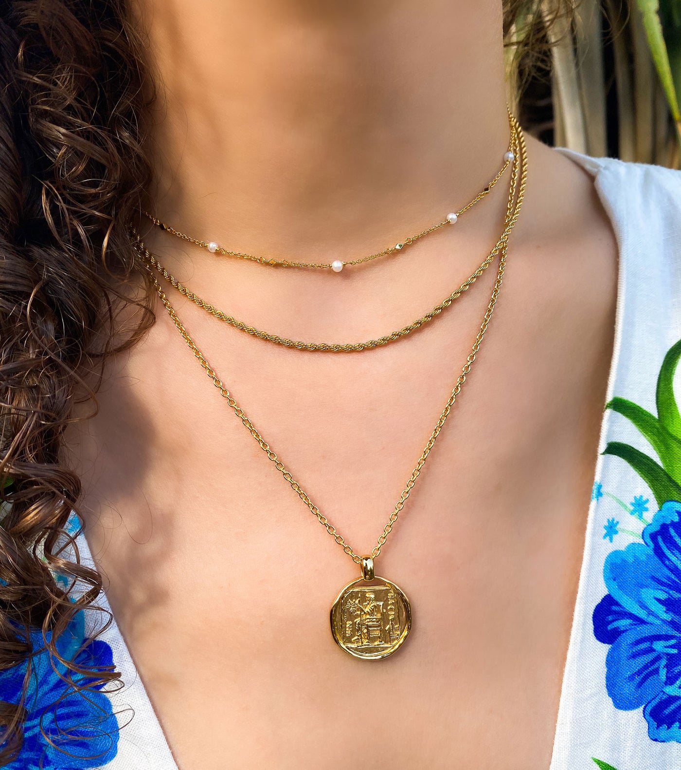 Model wearing gold pearl choker, gold twist rope necklace and gold plated sterling silver engraved greek coin pendant