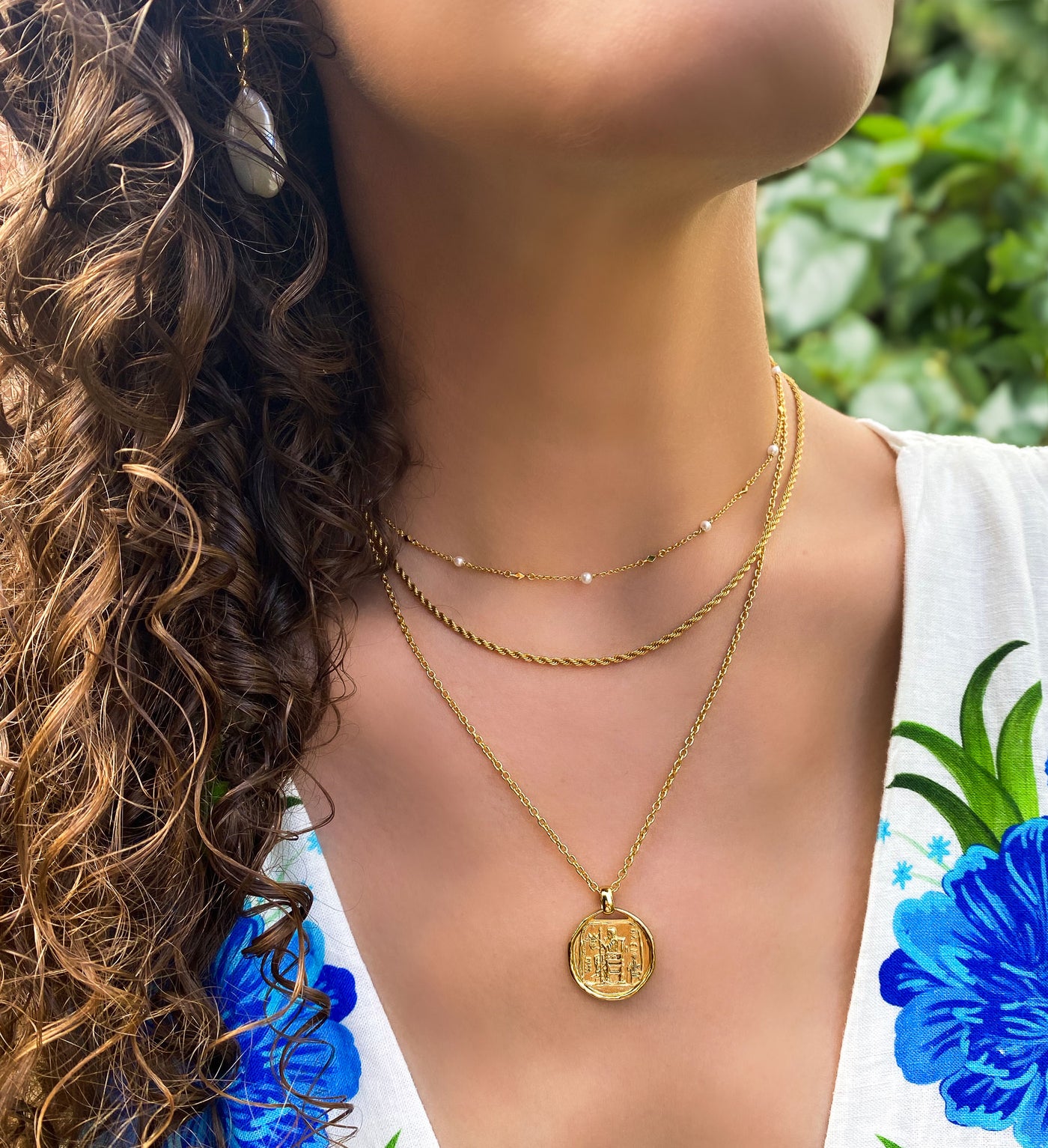 Model wearing gold pearl choker, gold twist rope necklace and gold plated sterling silver engraved greek coin pendant