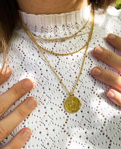 Model wearing gold labradorite beaded choker, gold twist rope necklace and gold plated sterling silver engraved greek coin pendant