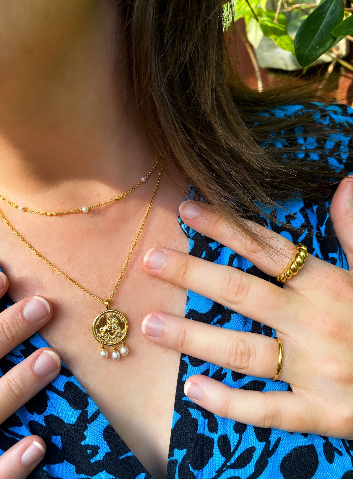 Model wearing gold plated sterling silver engraved horse coin pendant necklace with hanging freshwater pearls and beaded pearl choker 