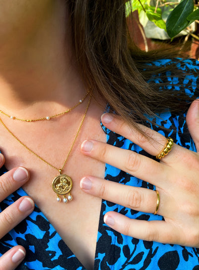 Model wearing gold plated sterling silver engraved horse coin pendant necklace with hanging freshwater pearls and beaded pearl choker 
