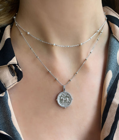 Model wearing sterling silver engraved tiger coin pendant necklace on bobble chain with pearl choker