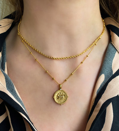 Model wearing layered gold plated sterling silver rope necklace and engraved tiger coin pendant on bobble chain