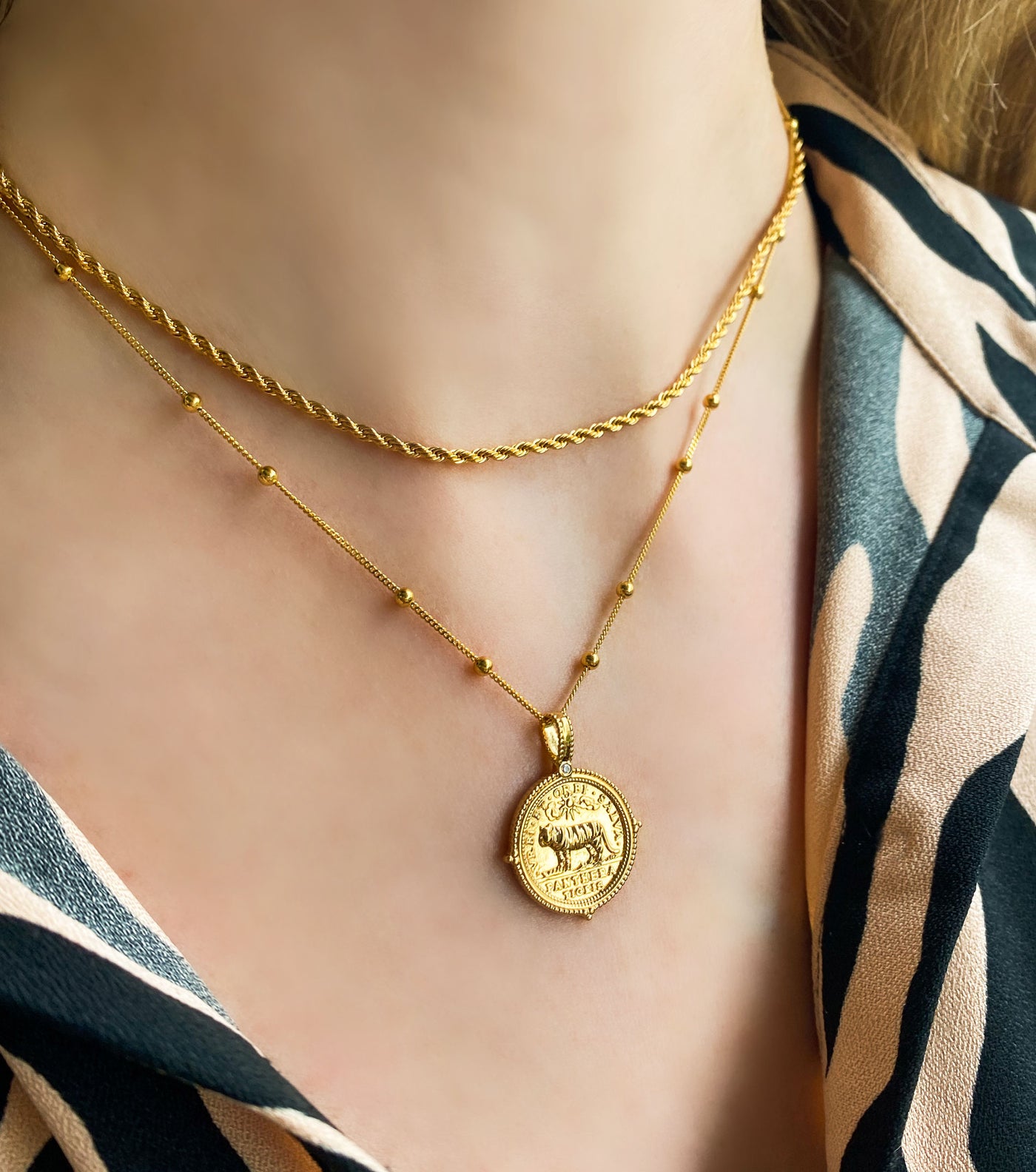 Model wearing layered gold plated sterling silver rope necklace and engraved tiger coin pendant on bobble chain
