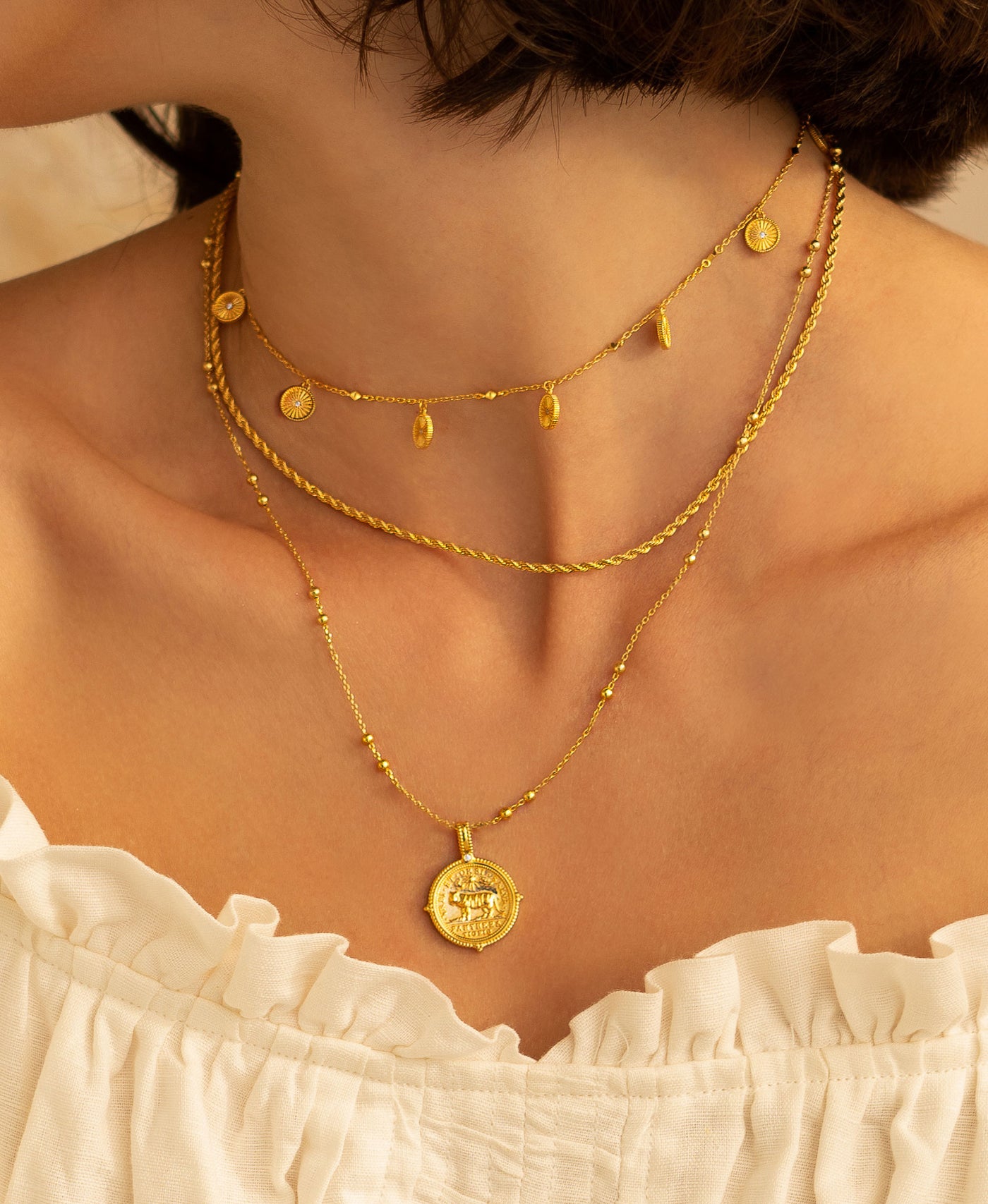 Model wearing layered gold plated sterling silver engraved coin choker, rope necklace and engraved tiger coin pendant on bobble chain