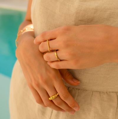 Model wearing simple gold plated sterling silver plain, minimal ring bands with chunky rope ring