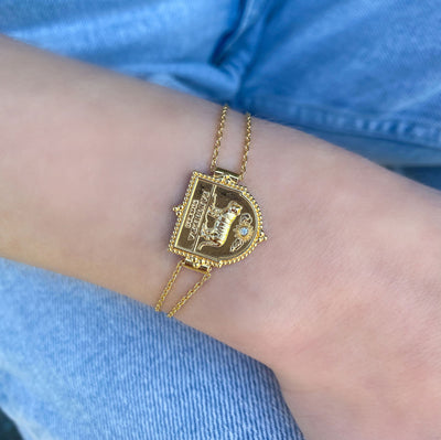 Model wearing gold plated sterling silver double chain bracelet featuring engraved tiger charm