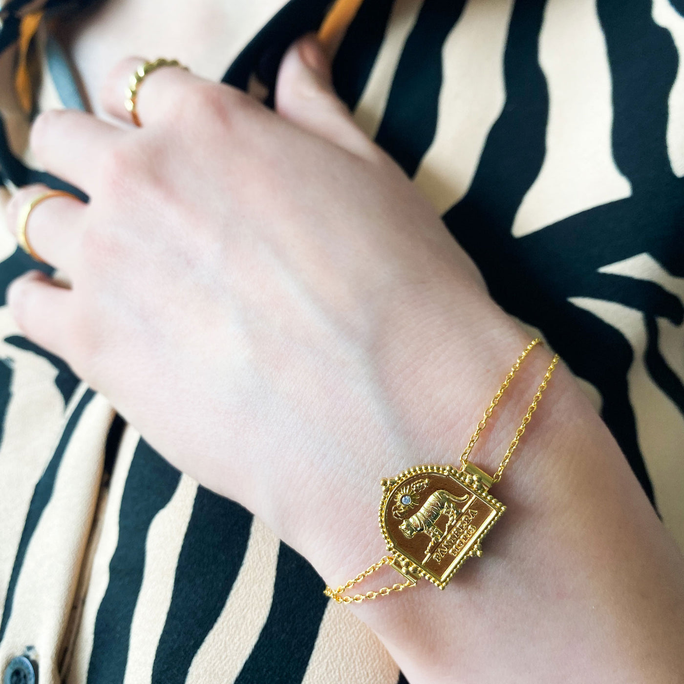 Model wearing gold plated sterling silver double chain bracelet featuring engraved tiger charm