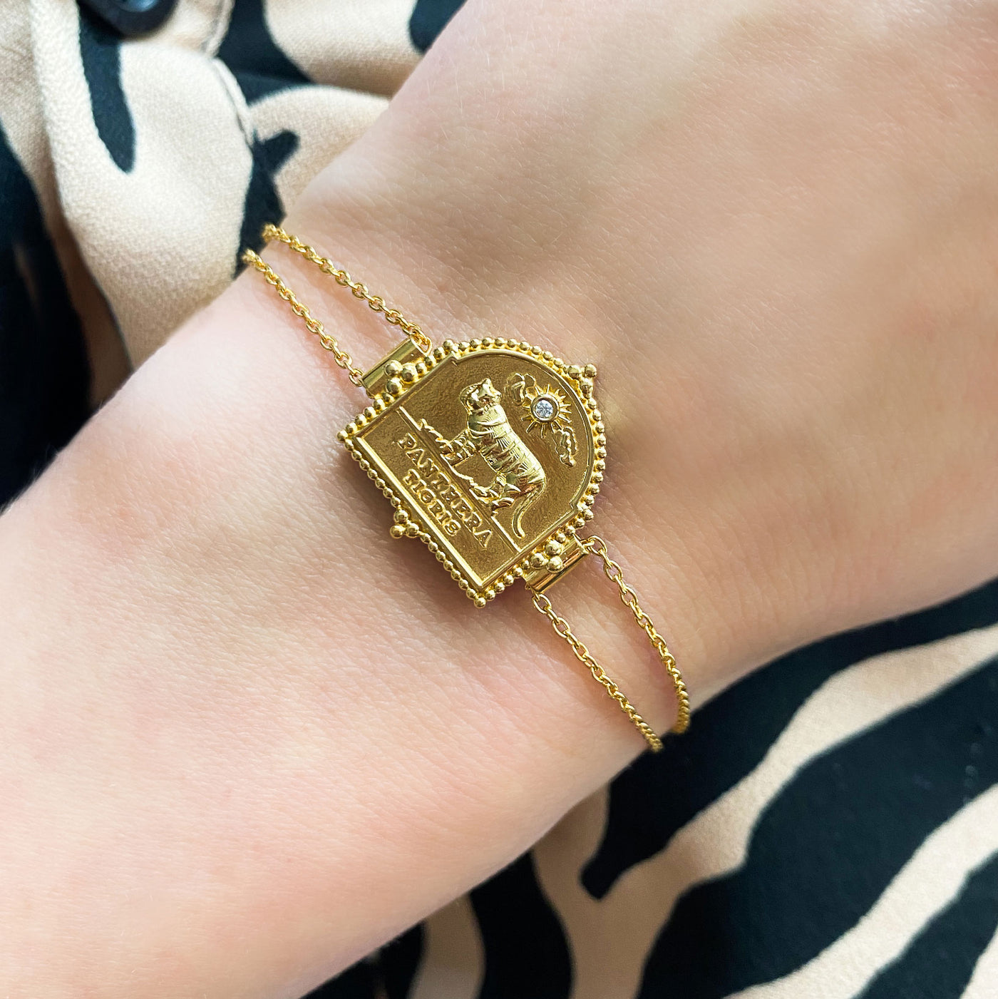 Model wearing gold plated sterling silver double chain bracelet featuring engraved tiger charm