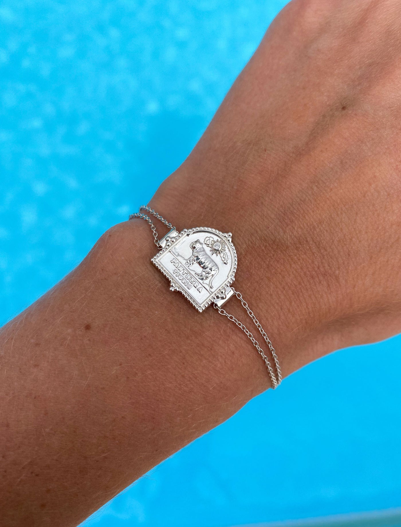 Model wearing sterling silver double chain bracelet featuring engraved tiger charm, against a blue background