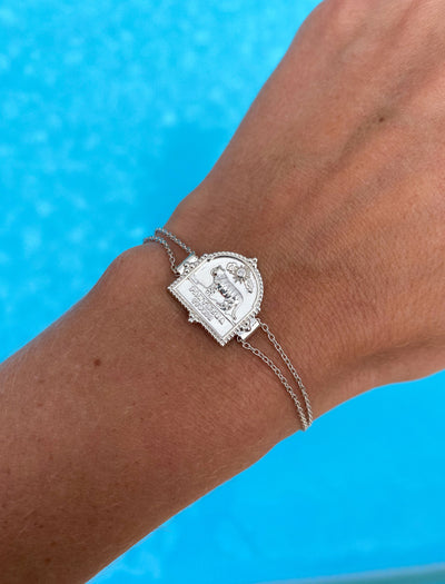 Model wearing sterling silver double chain bracelet featuring engraved tiger charm, against a blue background