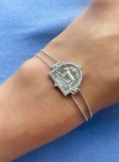Model wearing sterling silver double chain bracelet featuring engraved tiger charm, against a blue background