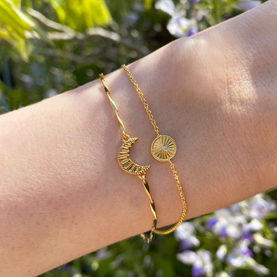 Model wearing gold plated sterling silver engraved set of 2 delicate sun and moon bracelets with CZ crystals
