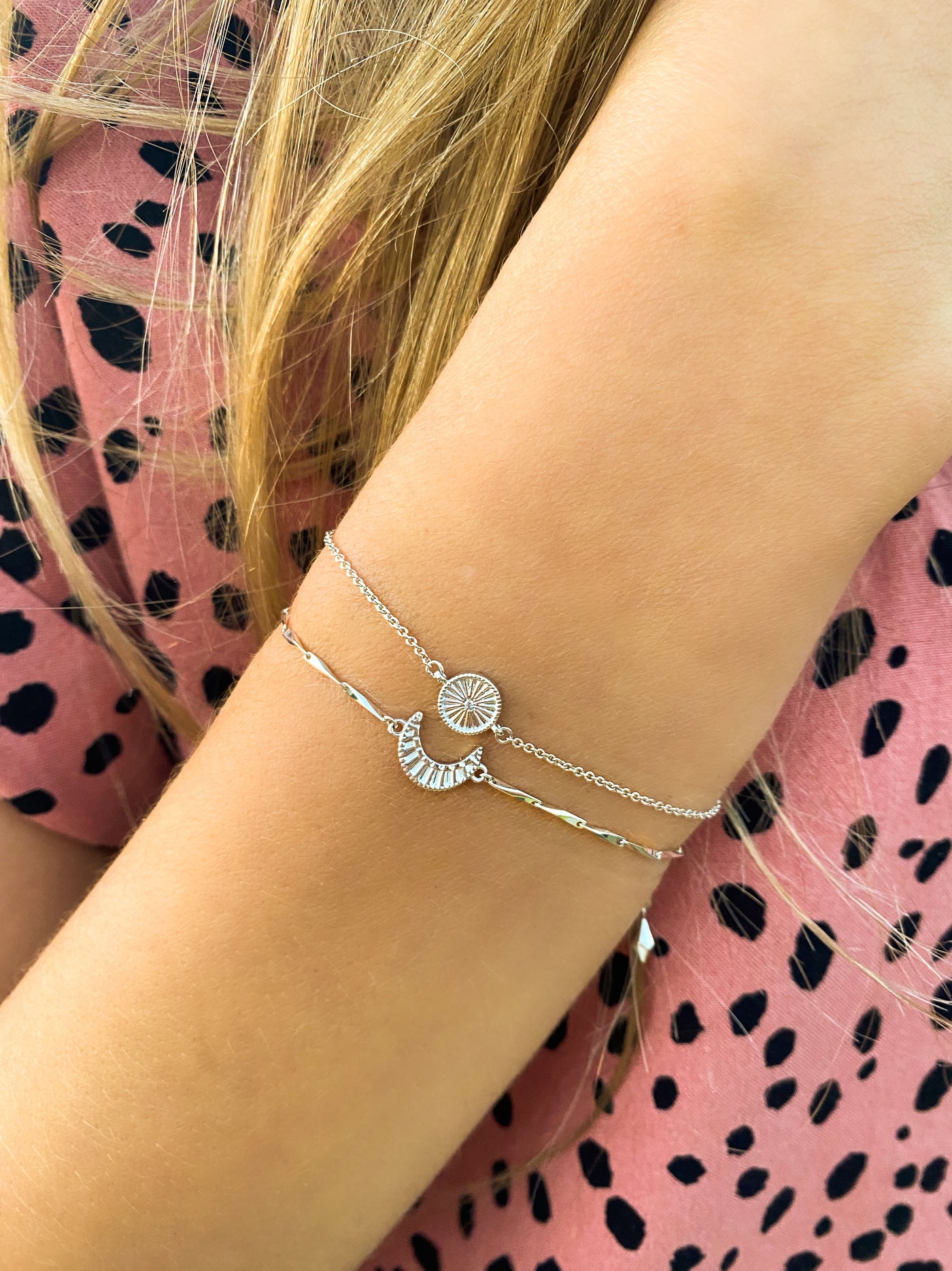 Model wearing sterling silver engraved set of 2 delicate sun and moon bracelets with CZ crystals