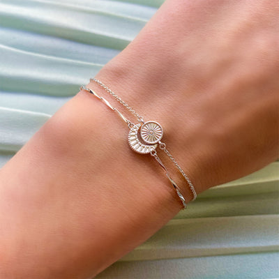 Model wearing sterling silver engraved set of 2 delicate sun and moon bracelets with CZ crystals