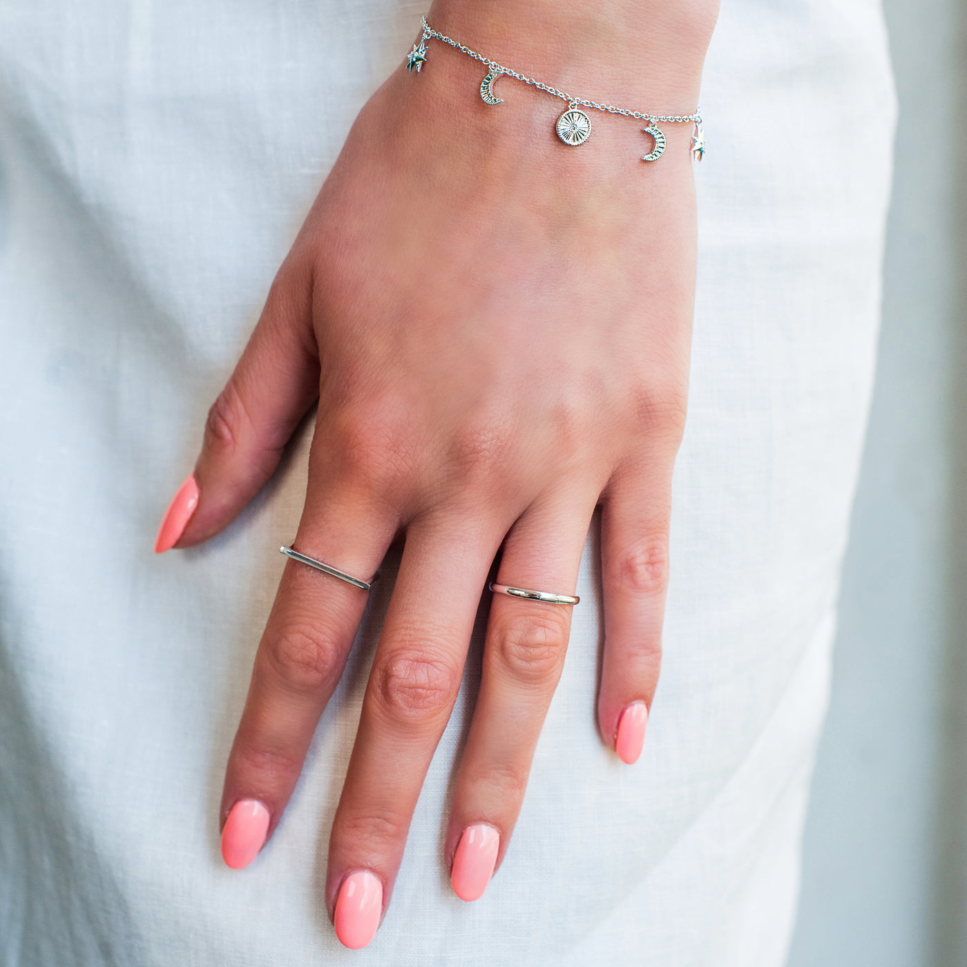 Model wearing sterling silver horseshoe shaped minimal plain ring and other ring band with moon and star charm bracelet
