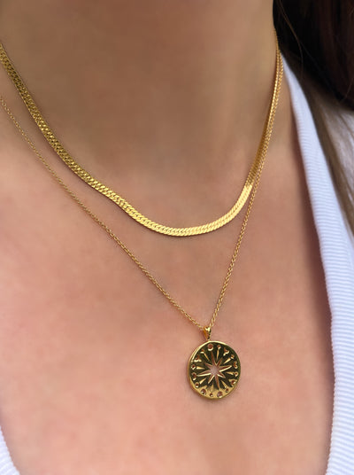 Model wearing gold filigree moon and star coin pendant with gold snake chain