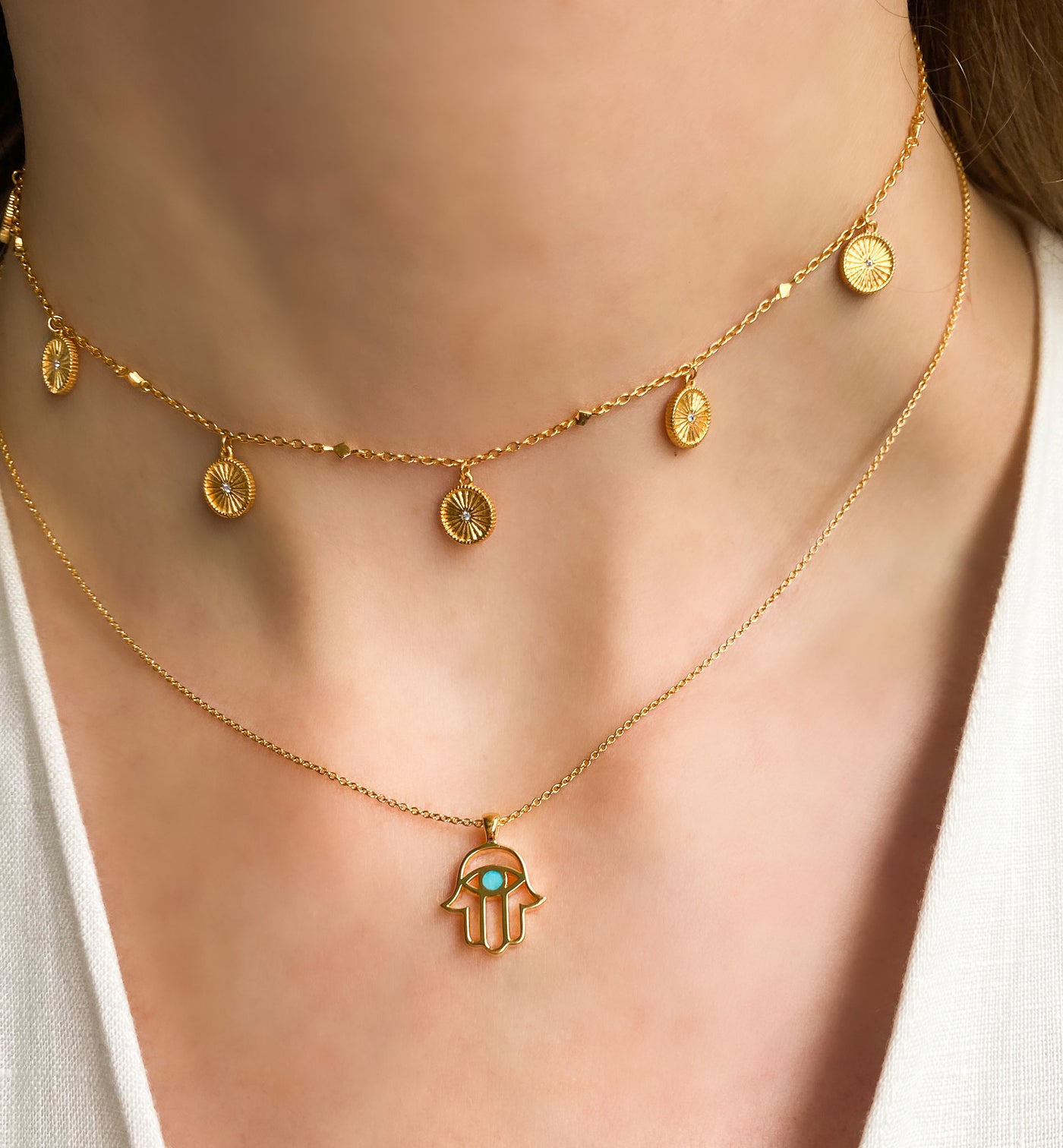 Model wearing gold plated sterling silver hamsa hand necklace with aquamarine semi-precious stone and coin choker 